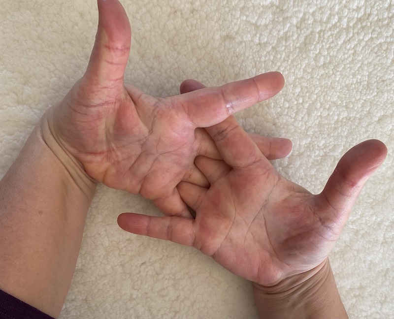 Photo of two hands with interlaced fingers.